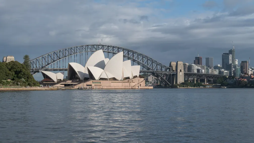 Operahuset og Harbour Bridge i Sydney set over havnens vand med skyskrabere i baggrunden