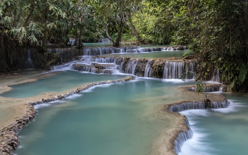 Turkise bassiner og små vandfald i trin ved Kuang Si i junglen nær Luang Prabang i Laos