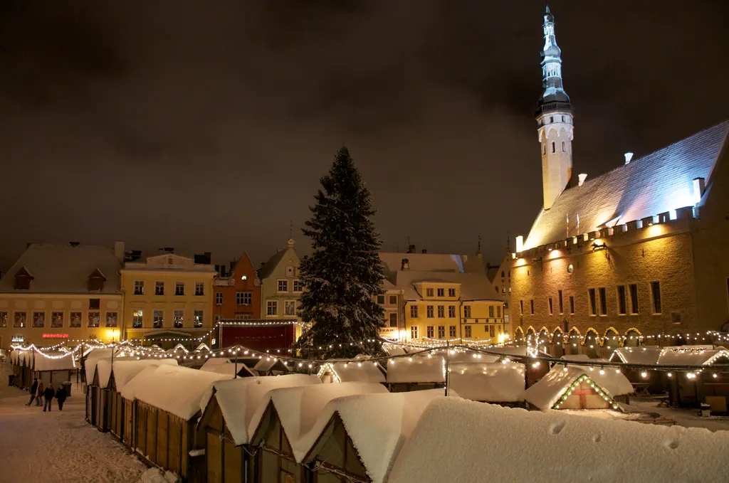 Snedækkede boder og juletræ på rådhuspladsen i Tallinn om aftenen