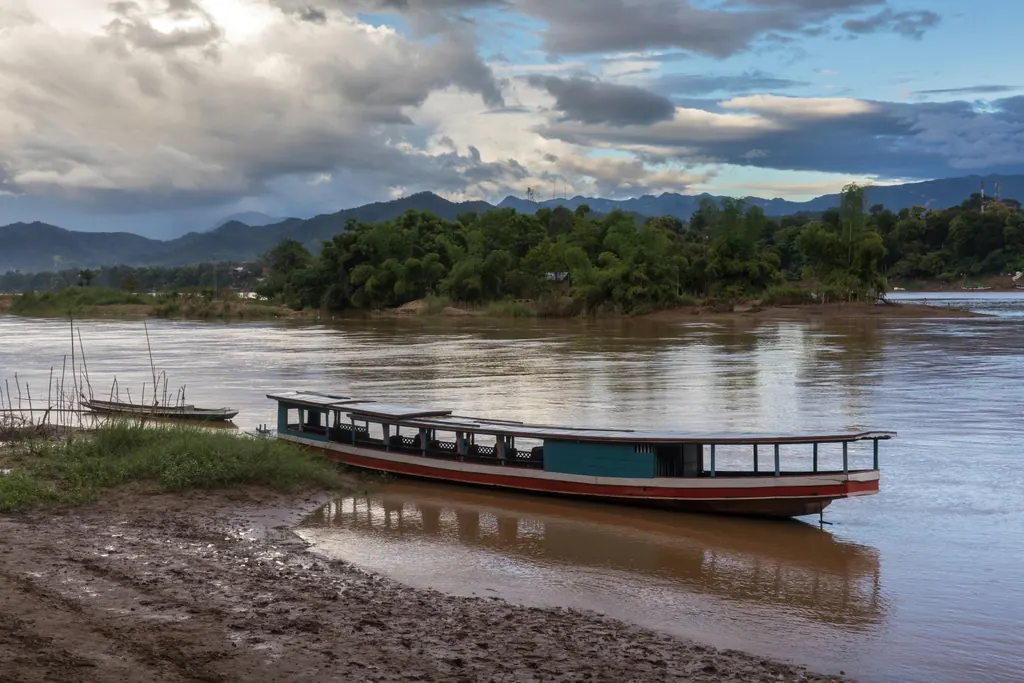 Træbåde ved bredden af Mekong i Luang Prabang en eftermiddag med skyer