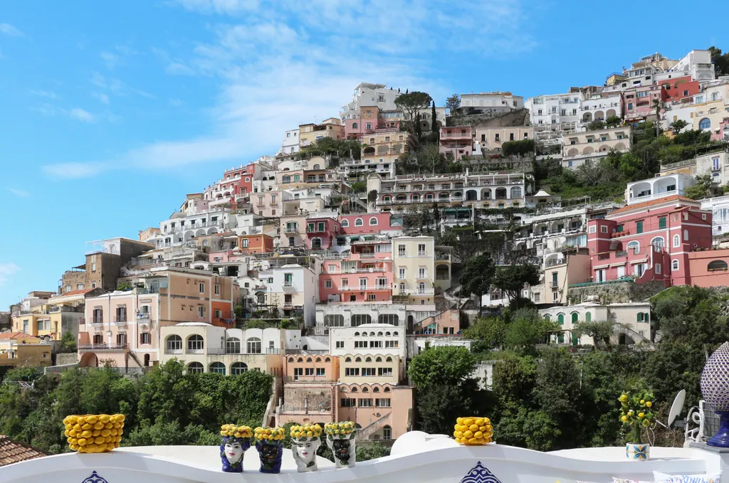 Pastelfarvede huse i terrasser på skrænten i Positano på Amalfikysten under en blå himmel