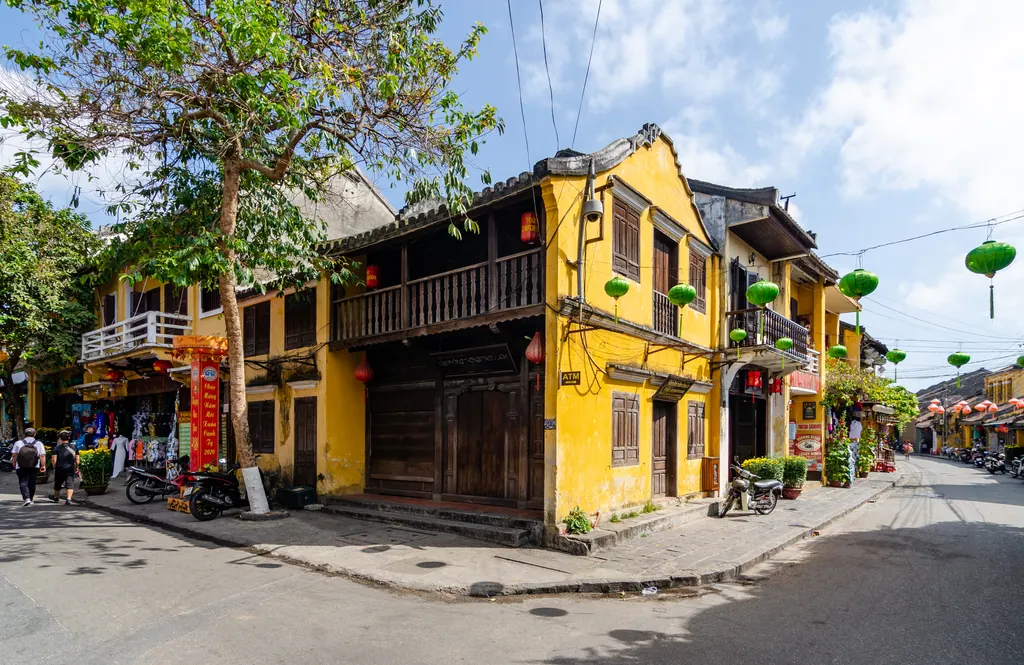 Gule gamle huse med grønne og røde lanterner i den gamle bydel i Hoi An i Vietnam