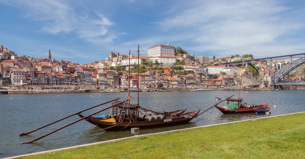 Traditionelle rabelo-både på Douro-floden med Portos farverige gamle bydel og Dom Luís I-broen i baggrunden