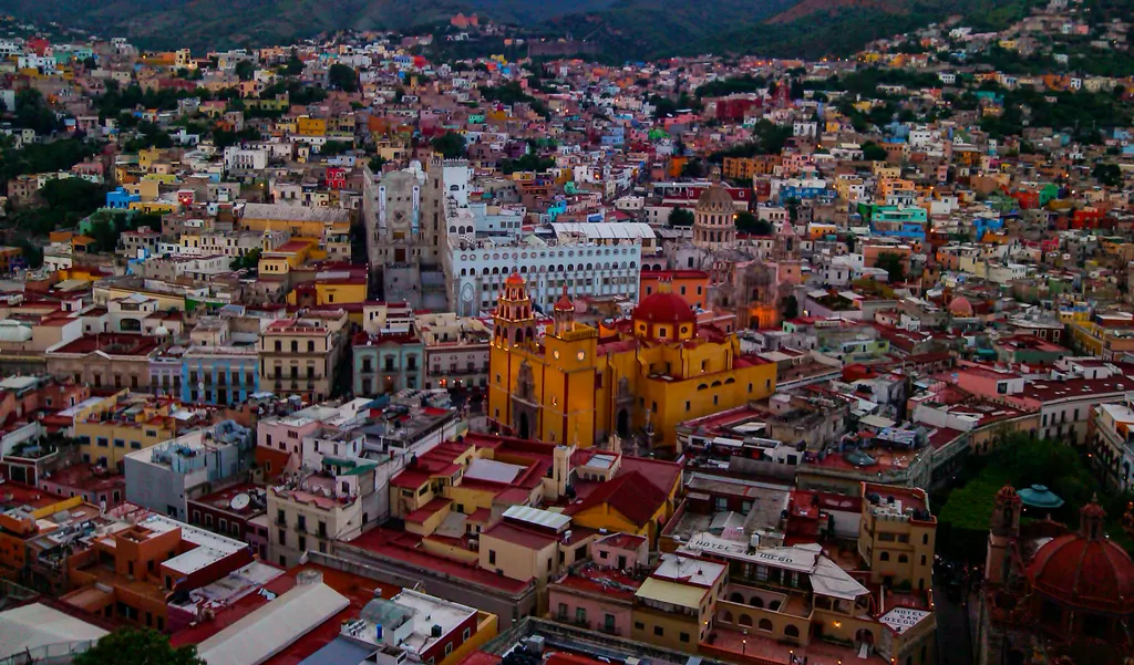 Guanajuato set fra oven i skumringen med farverige huse og den gule basilika midt i byen