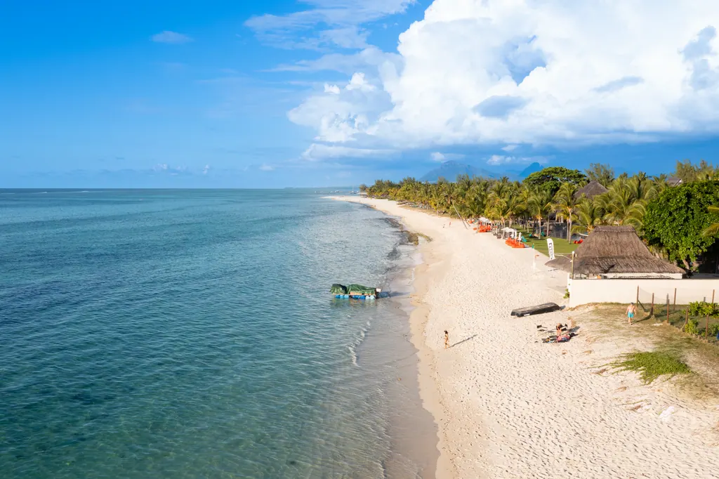 Turkist, lavt vand langs en lang hvid sandstrand med palmer ved Le Morne på Mauritius