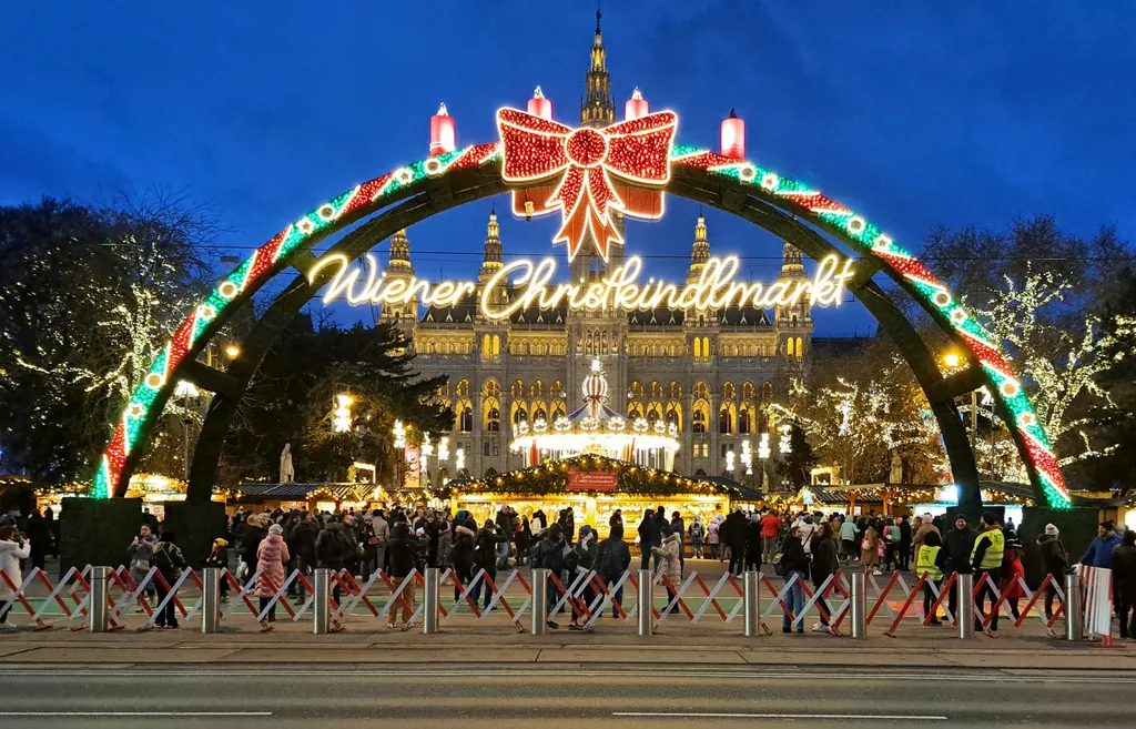 Oplyst indgangsbue til julemarkedet foran rådhuset i Wien i den blå time