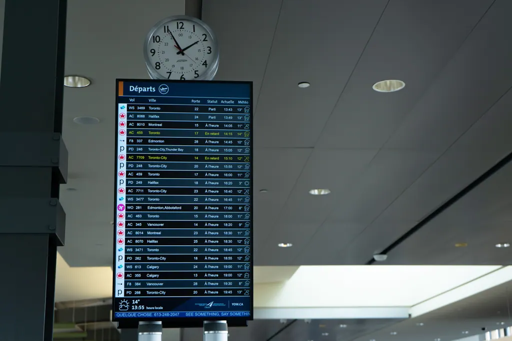 Afgangstavle i en lufthavn med et ur over og to fly markeret som forsinkede
